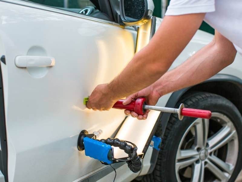 body shop technician pulling a dent at Alexandria Chevrolet Cadillac in Alexandria MN 